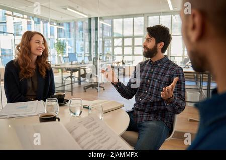 Smiling businessman talking with colleagues during a casual office meeting Stock Photo