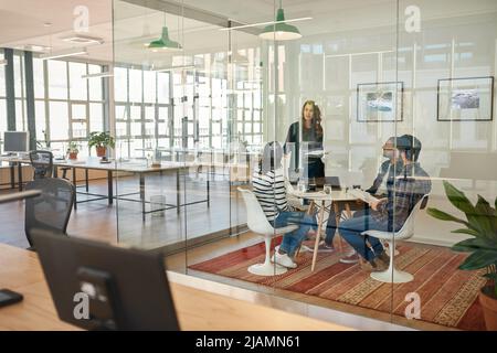Businessman talking to colleagues sitting around a table in an office Stock Photo