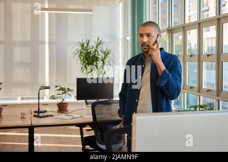 Confident young businessman talking on his phone in an office Stock Photo