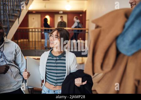 Smiling female student holding laptop by friend at university Stock Photo
