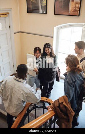 High angle view of multiracial students talking at staircase in university Stock Photo