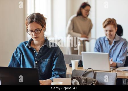 Dedicated female student using laptop while sitting at desk in classroom Stock Photo