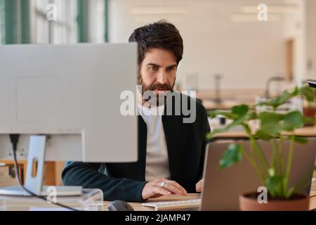 Focused young businessman working on a laptop at his office desk Stock Photo