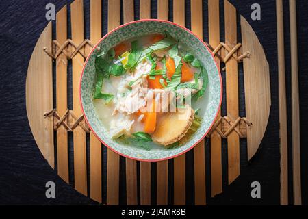 Asian chicken soup with vegetables and rice. Hot pot with chopsticks. Stock Photo