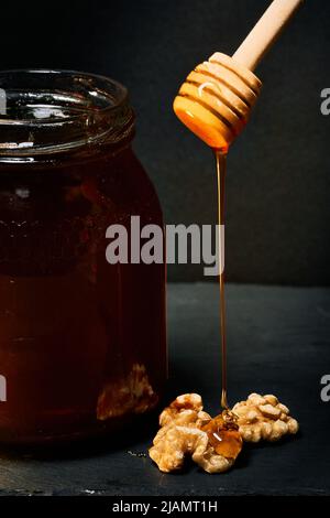 Jar with different tasty nuts and honey on green background, top