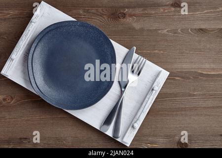 Dark ceramic plate and tray with cutlery on white tray and grunge wooden tables Stock Photo