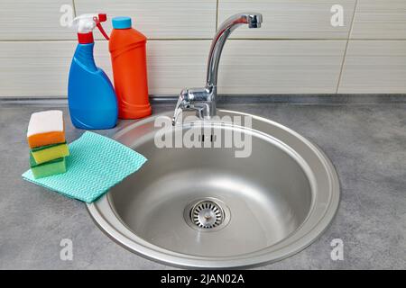 Round metal sink, cleaning agent, wipes and foam sponges Stock Photo