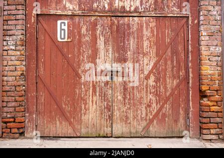 Old garage door in a white concrete wall. Gates made of wood painted with cracked green paint Stock Photo