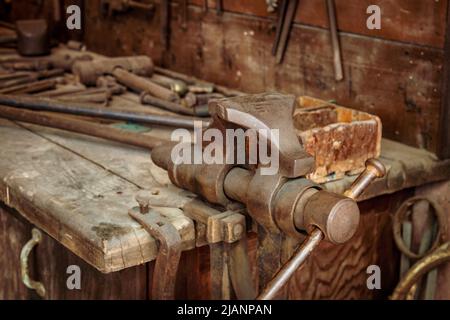 bench vice tool on metal workbench, vice grip on metallic table, professional clamp construction in workshop Stock Photo