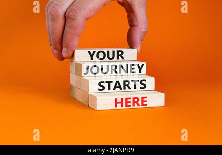 Your journey starts here symbol. Concept words Your journey starts here on wooden blocks on a beautiful orange table orange background. Business, moti Stock Photo