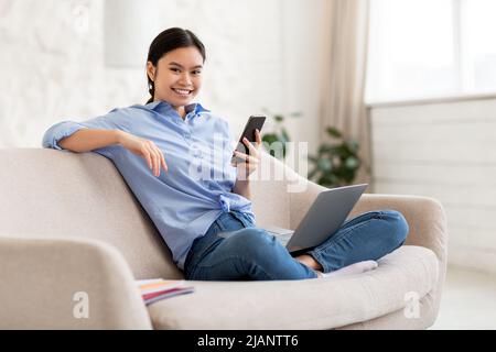 Young woman looking for job online, using smartphone and laptop Stock Photo