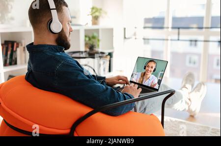 Millennial guy using wireless headset and laptop, calling business partner Stock Photo