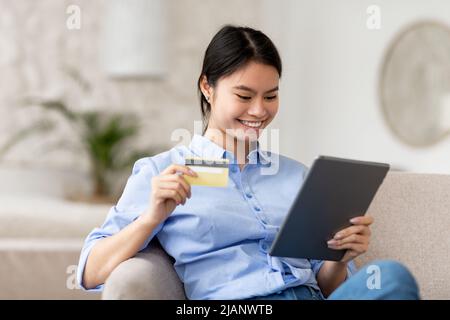 Cheerful japanese woman shopping online, using pad and credit card Stock Photo