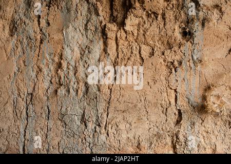 Clay aged dry texture from the interior wall of a dugout dirt garage. This is a macro view showing cracks with beige, green and blue tints of color. Stock Photo