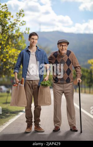 Young man helping a senior outdoors and carrying grocery bags Stock Photo