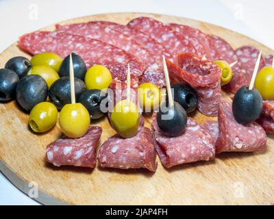 Slicing salami and olives on toothpicks. Slicing on a kitchen board Stock Photo