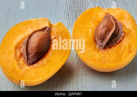 Two halves of a yellow apricot close-up on a light blue wooden table Stock Photo