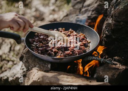 Cooking veal liver in pan at camp Stock Photo