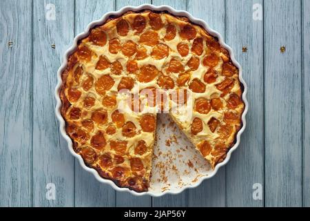 Open pie with cherry plum in a cream filling on a blue wooden table. Harvest festival Stock Photo