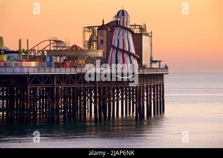 Brighton's Palace Pier, or BRIGHTON PIER.  Brighton & Hove, Sussex, England, UK. Photographed at dusk with the helter skelter and amusements. Stock Photo