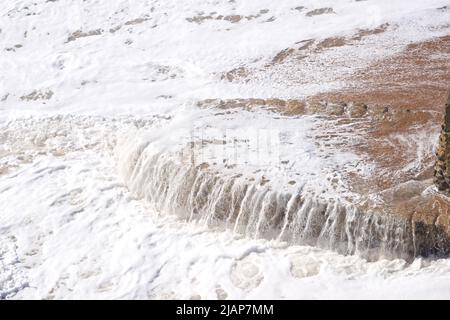 Water spilling off the base of a sea defence groyne on Brighton beach, East Sussex, England, UK Stock Photo