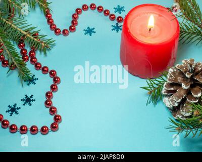 New Year card. Christmas card on blue background. Fir branches. Decorations for the holiday. Red beads, candle and fir cones Stock Photo