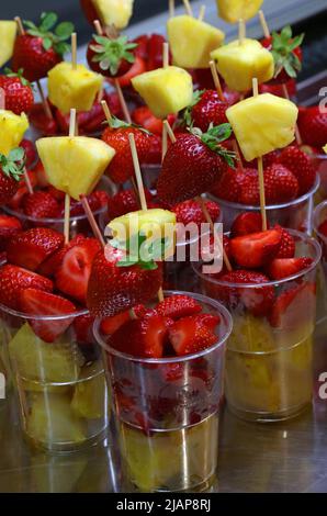 skewers of fresh chunky fruit with strawberries and pineapple inside glasses for sale in tropical beach bar in summer Stock Photo