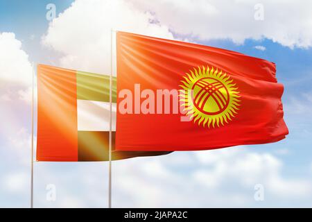Sunny blue sky and flags of kyrgyzstan and uae Stock Photo