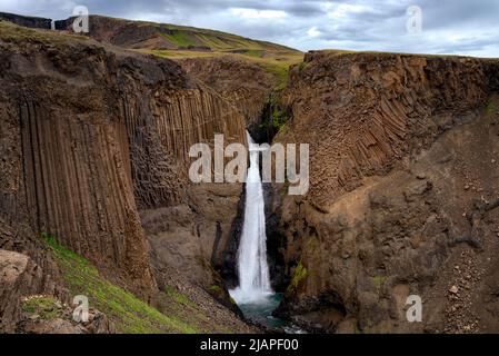 Litlanesfoss Waterfall, Iceland. Litlanesfoss is a waterfall in Hengifoss‡ in Flj—tsdalur, Eastern Iceland, also known as Stu?labergsfoss. The waterfall is about 30 meters high and forms an apron in a cliff. The waterfall is in a large rock choir with an unusually regular supporting rock made of high and straight columns.  The Hengifoss waterfall can be seen in the distance, top  left. Stock Photo