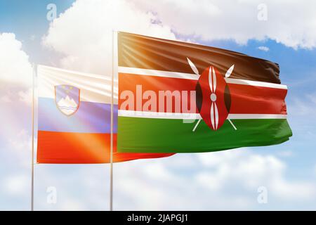 Sunny blue sky and flags of kenya and slovenia Stock Photo