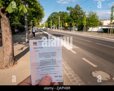 9 Euro Ticket at a cable car station for public transport. Holding the ticket and look at it. The 'Deutschlandtarif' is part of the 'Entlastungspaket' Stock Photo