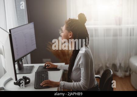 Young concenrated woman coder working on computer at home coding java script algorithm Stock Photo