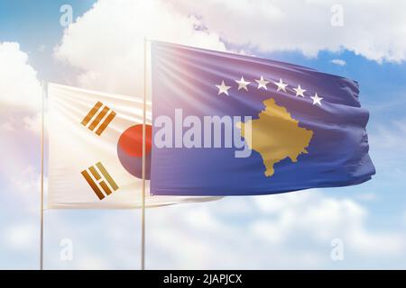 Sunny blue sky and flags of kosovo and south korea Stock Photo