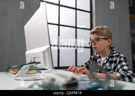 Schoolboy using computer in classroom at school Stock Photo