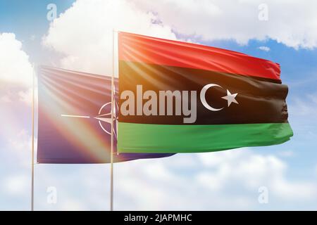 Sunny blue sky and flags of libya and nato Stock Photo