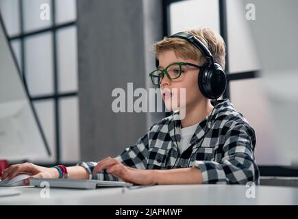 Schoolboy using computer in classroom at school Stock Photo