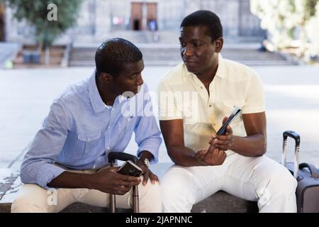 African american travelers resting and using smartphones Stock Photo