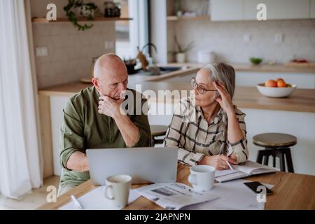 Stressed senior couple calculate expenses or planning budget together at home. Stock Photo