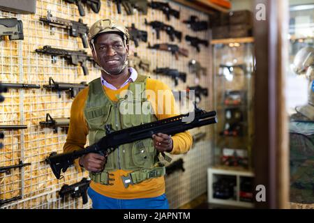 African american man in army uniform with weapon in military shop Stock Photo