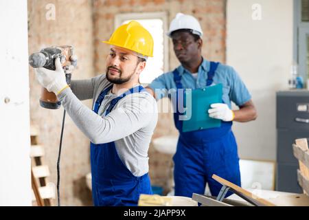 Man construction worker using demolition hammer in apartment Stock Photo