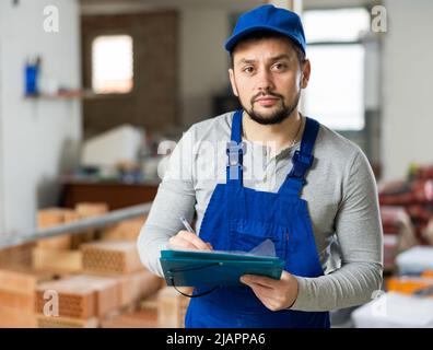 Focused contractor inspecting rooms and taking notes during renovation Stock Photo