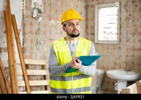 Focused supervisor taking notes while inspecting construction site Stock Photo