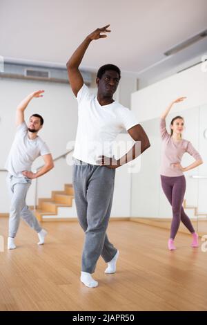 African-american man practicing classical dance moves with group Stock Photo