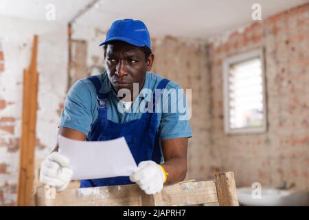 Man construction worker with document inside apartment Stock Photo
