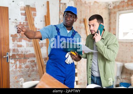 Builder having conversation with designer about working plan Stock Photo