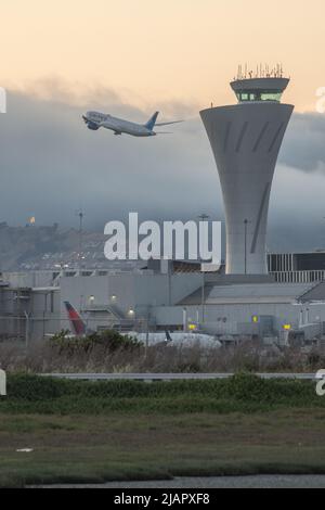 The airport traffic control tower at San Francisco international airport (SFO) in the Bay area of California with a plane taking off in the background Stock Photo