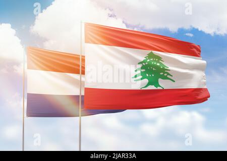 Sunny blue sky and flags of lebanon and netherlands Stock Photo