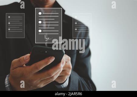 businessman holding smartphone business digital signing documents on virtual screen. Stock Photo