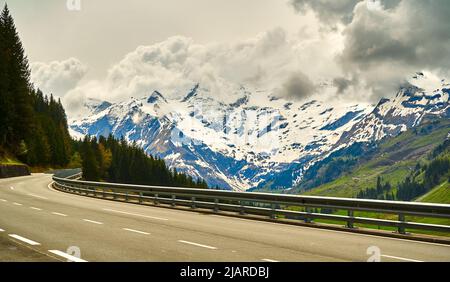 Cloudy Dachstein mountains in Austria with the high alpine road in the foreground during a road trip through the Alps Stock Photo