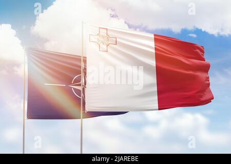 Sunny blue sky and flags of malta and nato Stock Photo